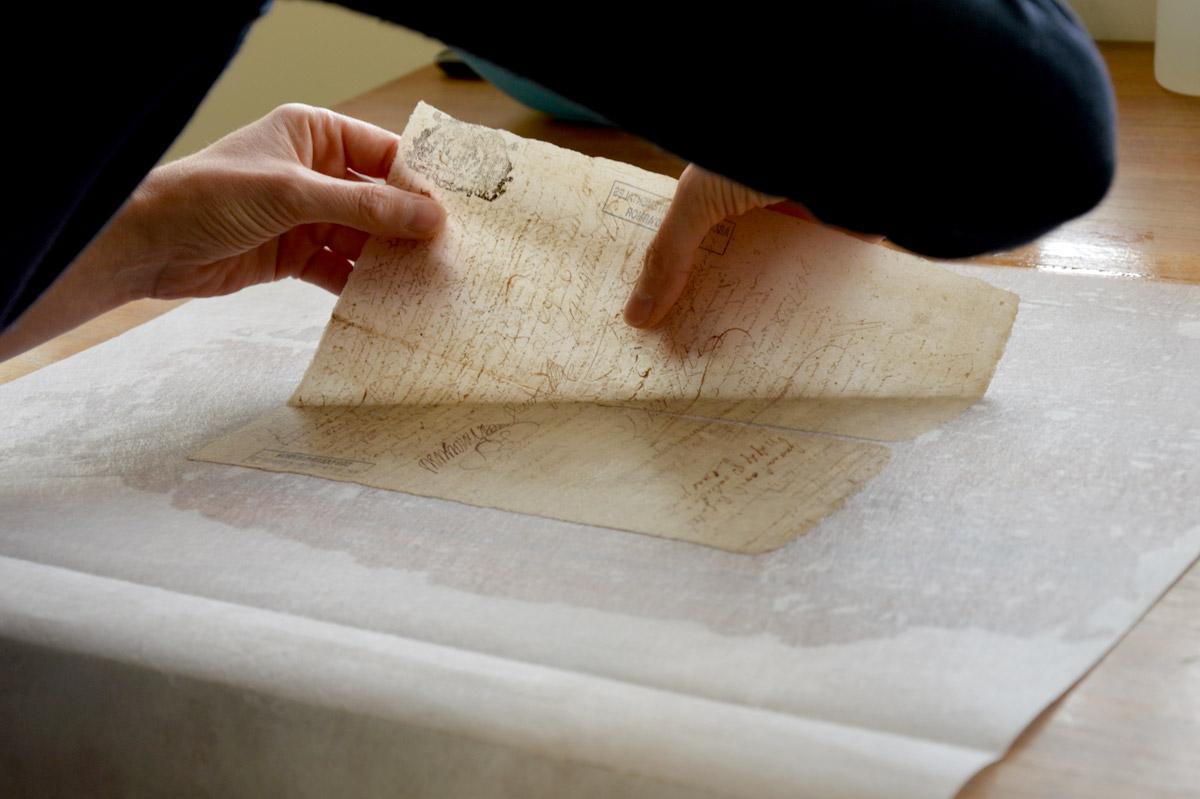 La restauratrice est au chevet d'un document endommagé par le temps. (AD 22, 2016)